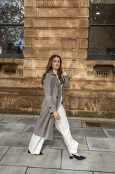 a lady in a white top, a grey long coat and a pair of white wide leg pants